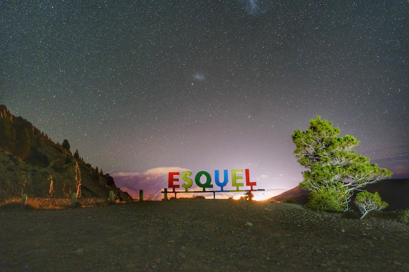 Cartel de Esquel bajo un cielo estrellado con la Nube de Magallanes